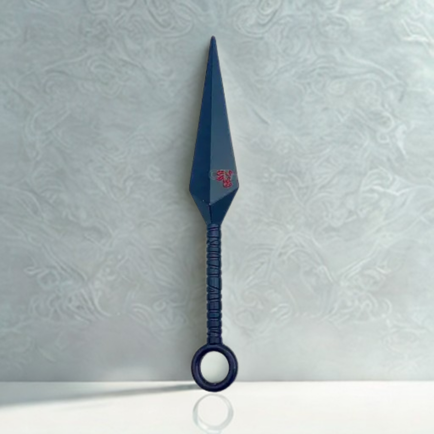 Naruto Asuma's Chakra Blade replica with black metallic finish and red kanji symbol, displayed vertically against a textured grey background