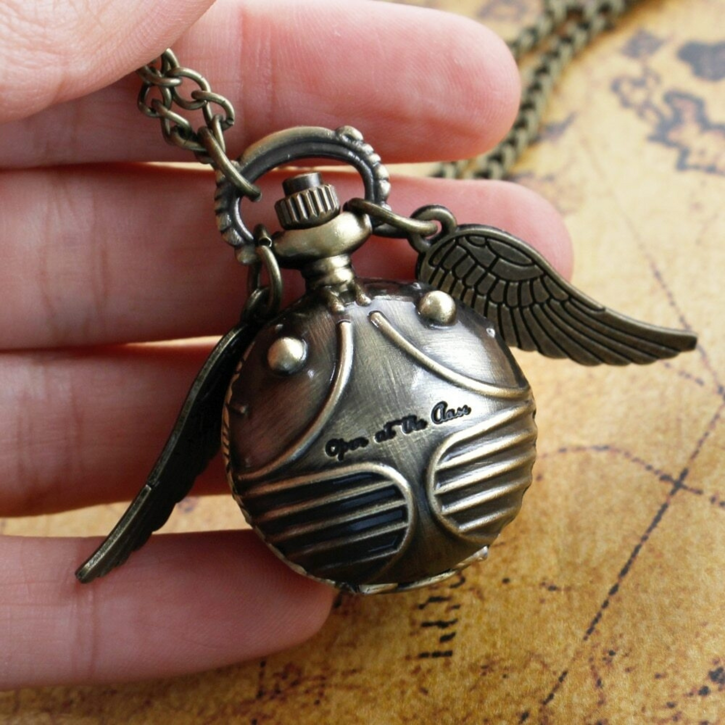 Golden Snitch pocket watch necklace with wings – Harry Potter themed collectible on golden mirror