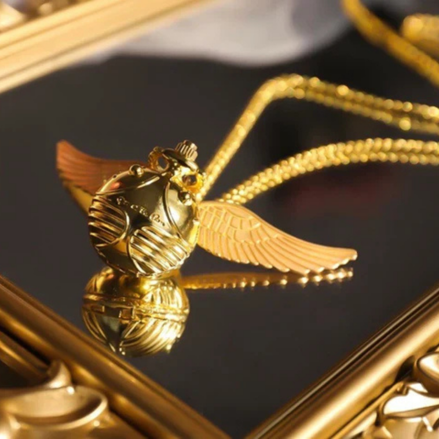 Golden Snitch pocket watch necklace with wings – Harry Potter themed collectible on golden mirror
